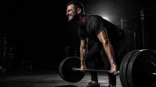 Homem superando esforço em treino difícil, academia escura e dramática