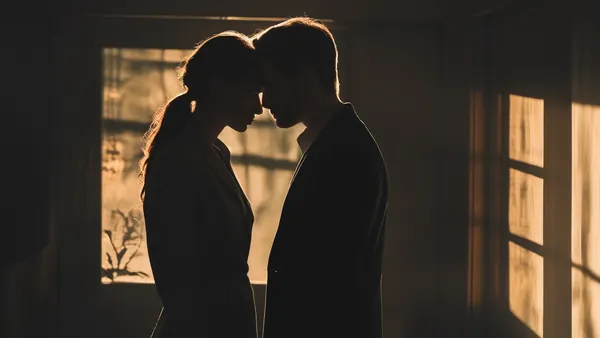 Silhueta de casal em quarto escuro com luz quente ao fundo, imagem discreta